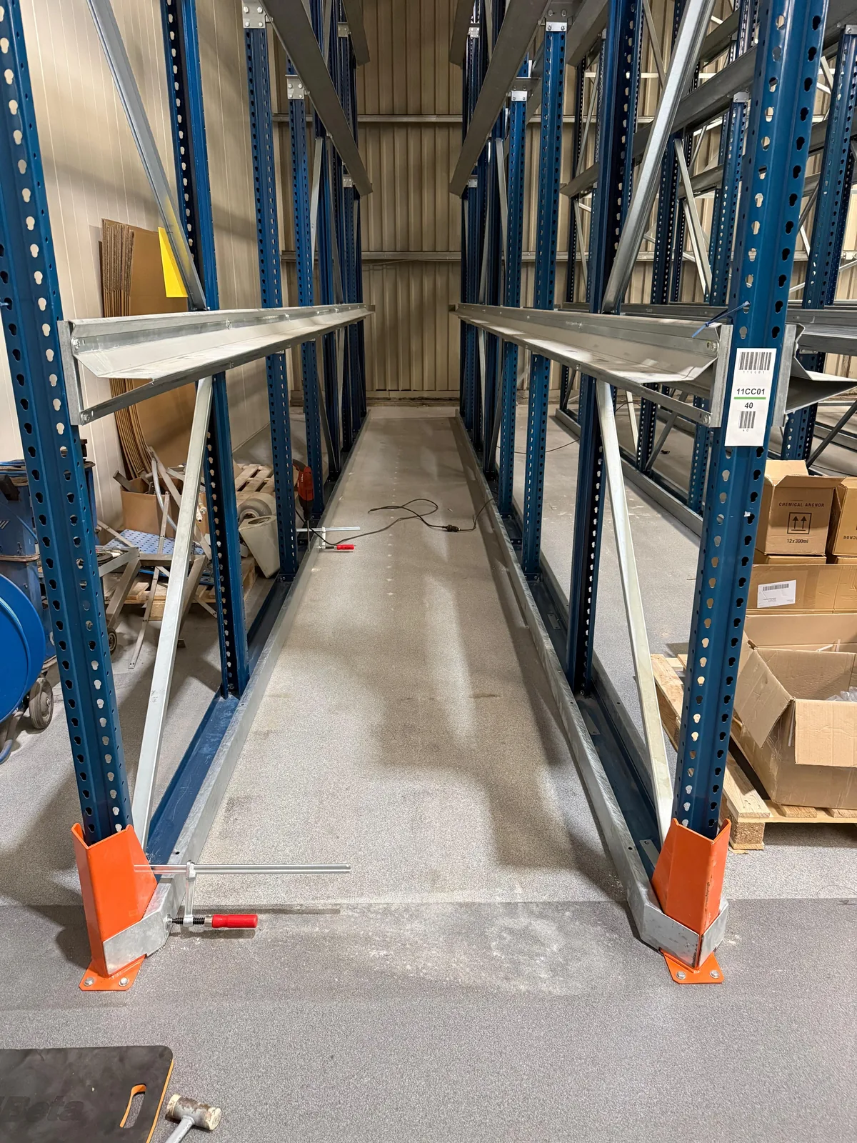 Stellingframe met oranje aanrijbeveiliging op de voetplaten en dozen chemisch anker op de achtergrond &mdash; Tiel