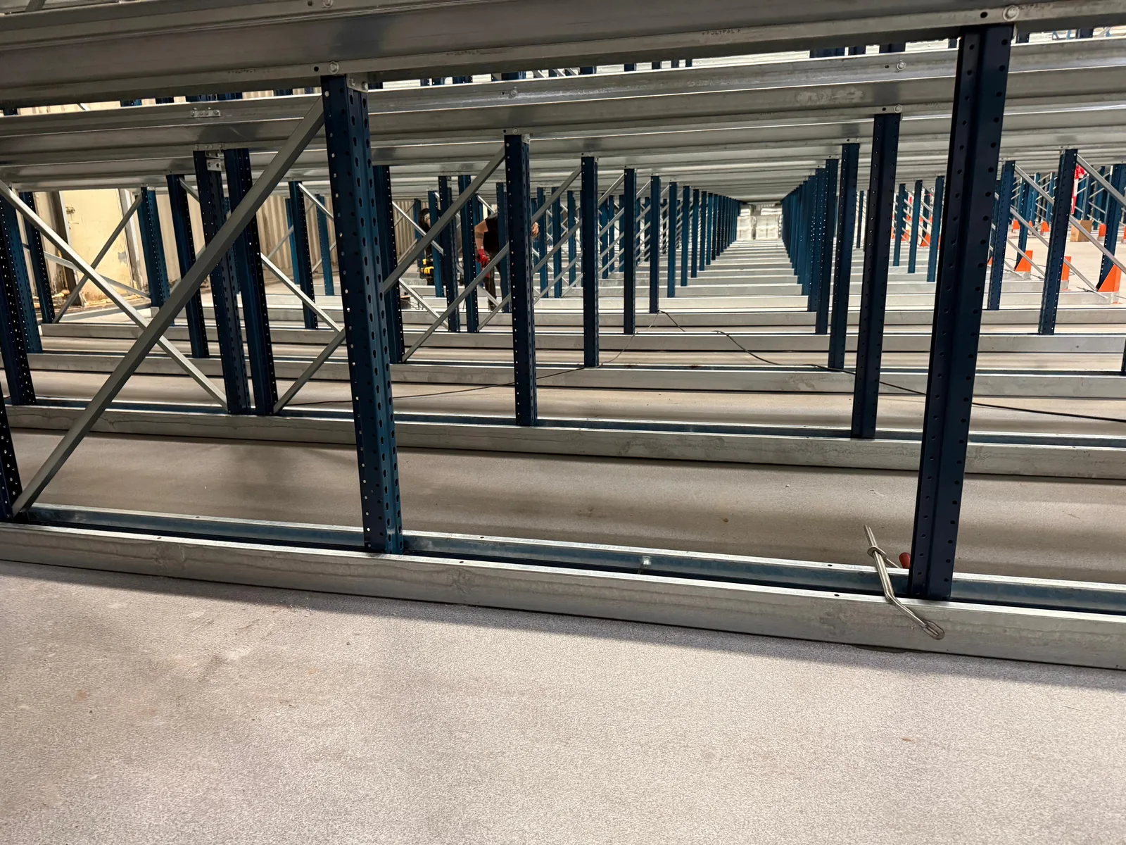 Zicht onder de stellingen door over de volle lengte van de hal, met de verankerde voetplaten &mdash; Tiel