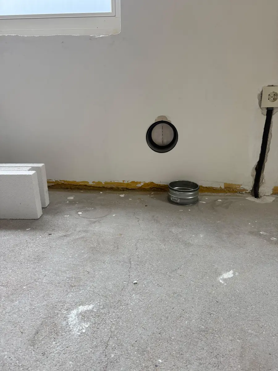 Afzuigkap gat boren Zwolle &mdash; Afzuigkapdoorvoer laag in de wand van een ruimte in aanbouw, met een stuk spirobuis op de vloer