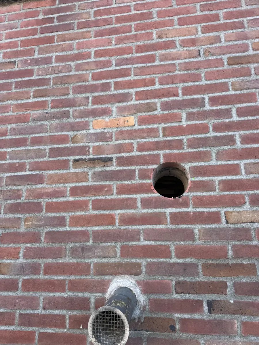 Afzuigkap gat boren Helmond &mdash; Nieuw rond afzuigkapgat in oude rode baksteen, met daaronder een oude doorvoer met gaas