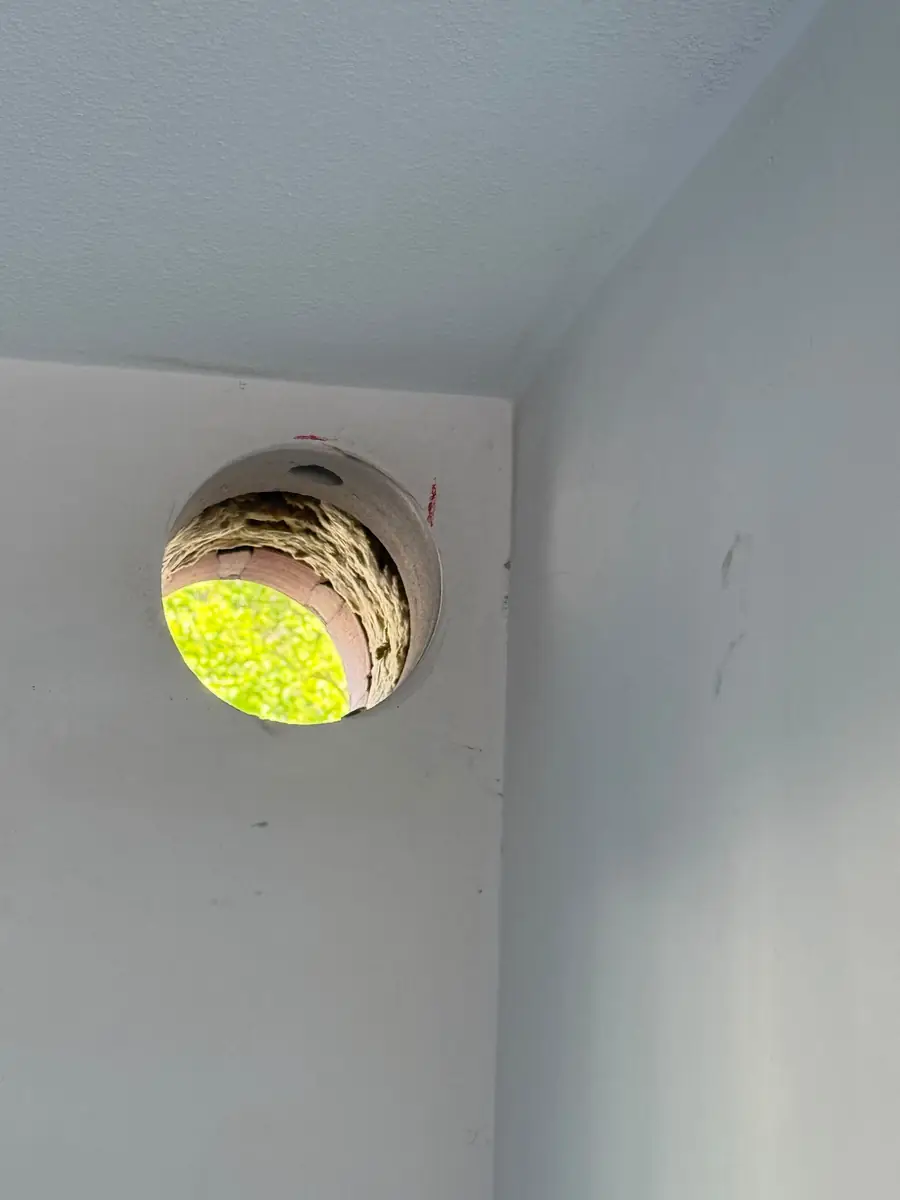 Afzuigkap gat boren Echt-Susteren &mdash; Afzuigkapgat in de hoek onder het plafond, met de lagen van de muur zichtbaar in de boring