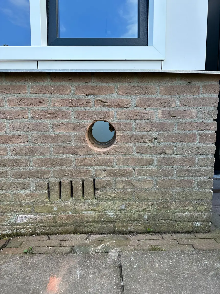 Afzuigkap gat boren Horst aan de Maas &mdash; Afzuigkapgat laag onder een raam, met daaronder de open stootvoegen van de spouw