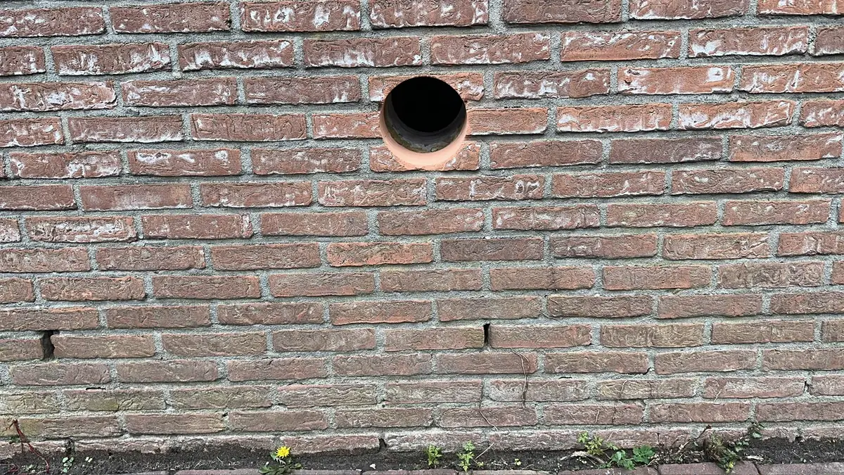 Afzuigkap gat boren Sittard-Geleen &mdash; Afzuigkapgat laag in een rode bakstenen gevel, vlak boven de grond