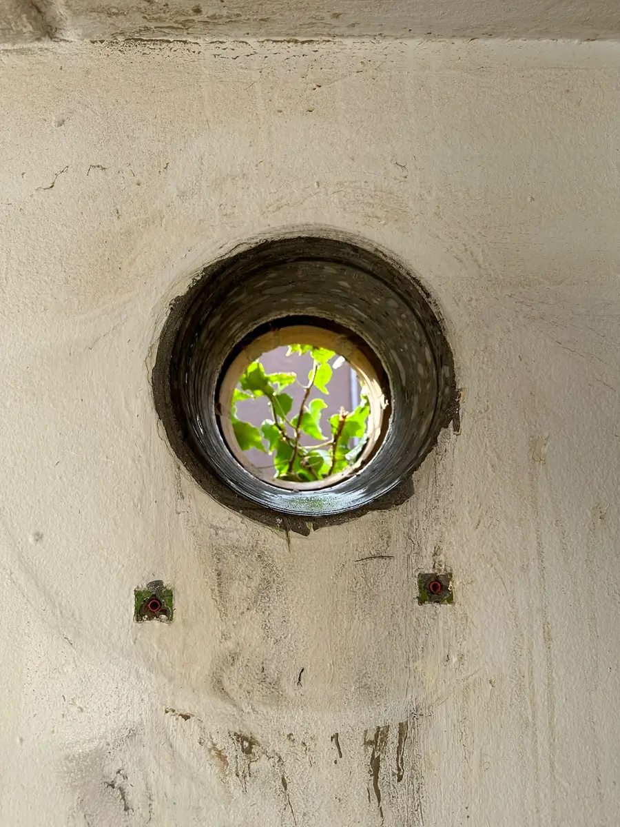 Afzuigkap gat boren Beekdaelen &mdash; Afzuigkapgat met een zwarte doorvoerring in een lichte wand, met twee pluggen eronder