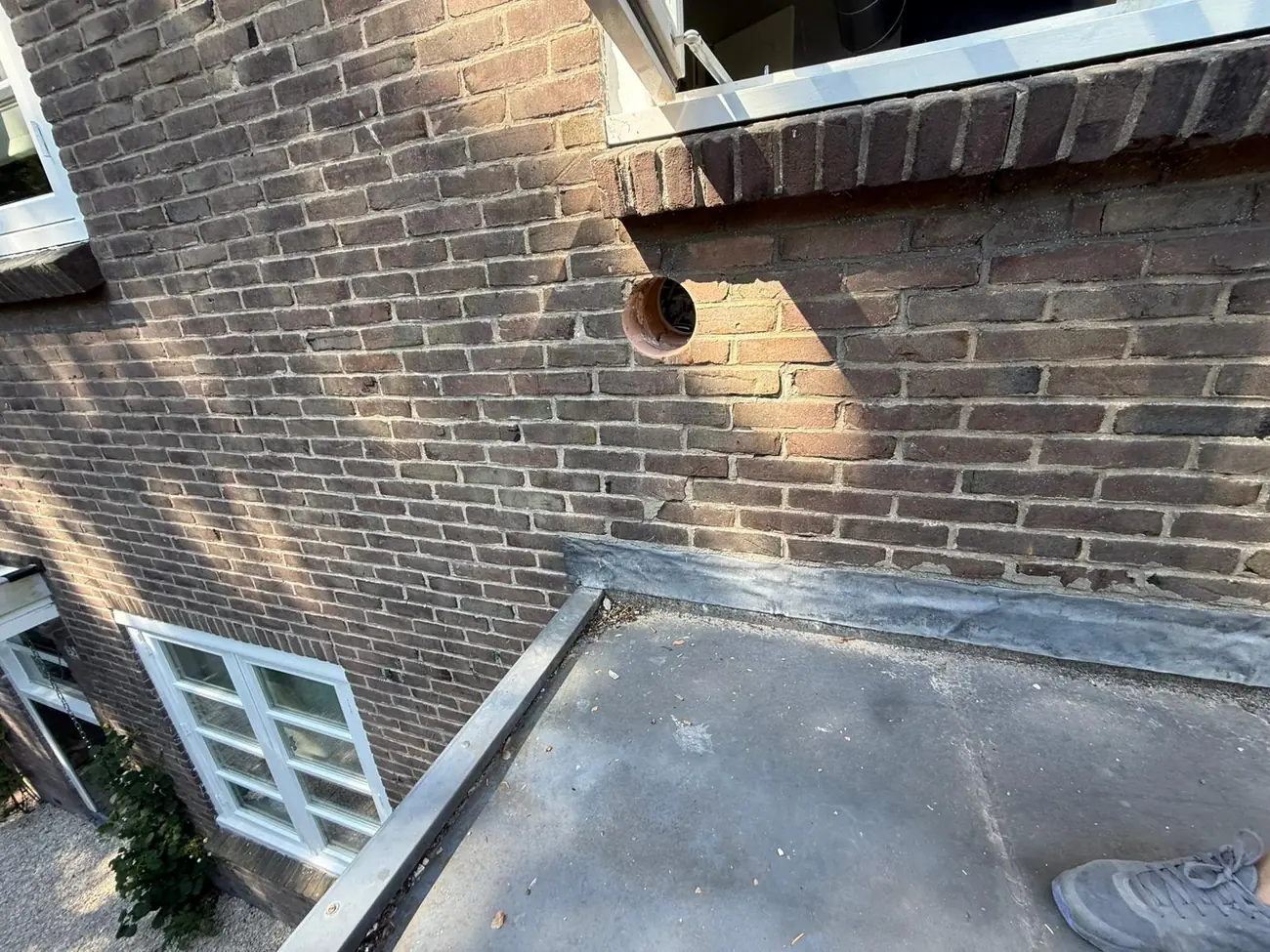Airco doorvoer geboord door de bakstenen muur in Vught &mdash; ronde wanddoorvoer met doorvoerbuis voor een mobiele airco