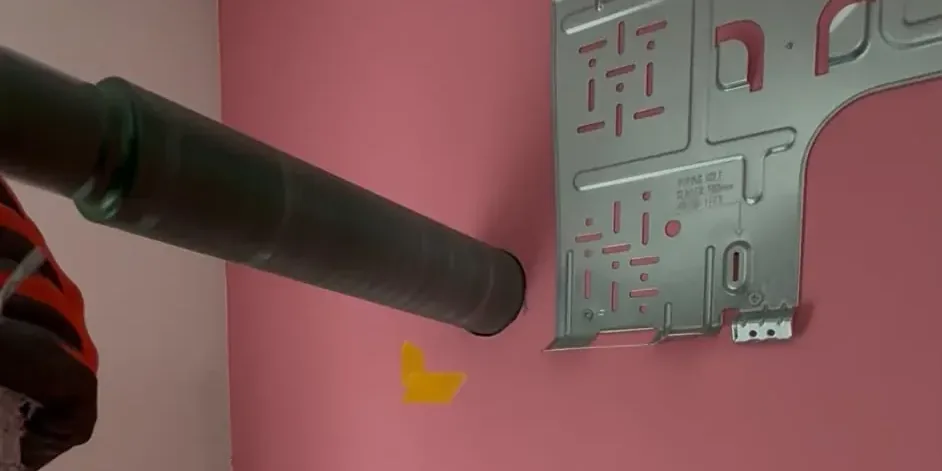Diamantkernboor tegen de binnenmuur, links onder de ophangplaat van een split-airco, op de plek van het leidinggat