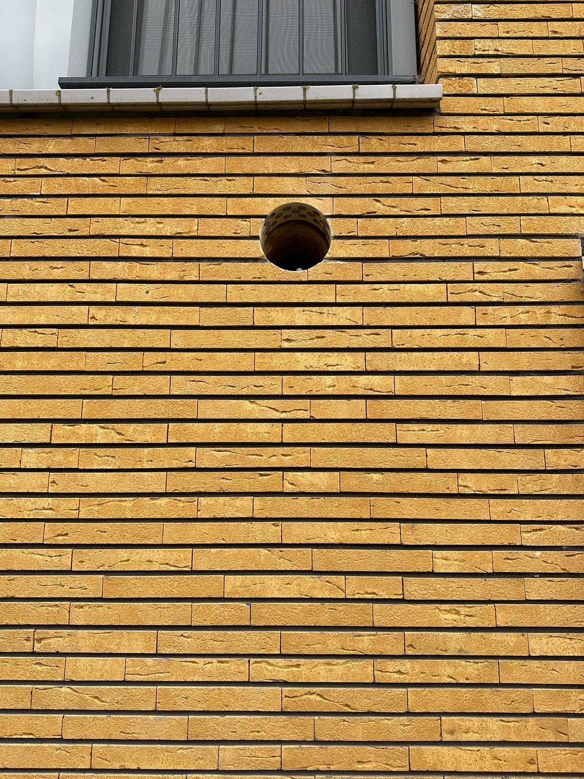 Kernboring in gele bakstenen buitengevel