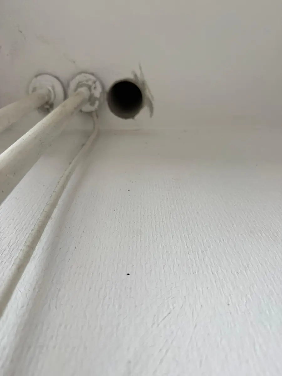 Betonboringen Bergen (Limburg) &mdash; doorvoer voor een ventilatiekanaal naast witte buizen bij het plafond