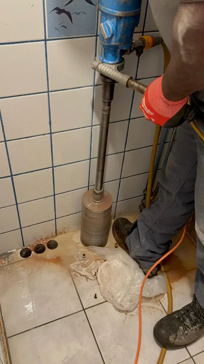 Betonboringen Bergen op Zoom &mdash; vloerboring met statief in een betegelde ruimte, met drie gaten in de hoek