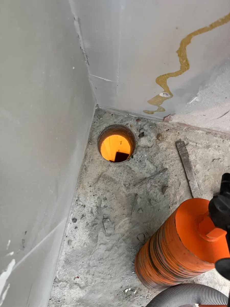 Betonboringen Best &mdash; vloerboring in de hoek van een kamer, met de oranje boorkroon ernaast