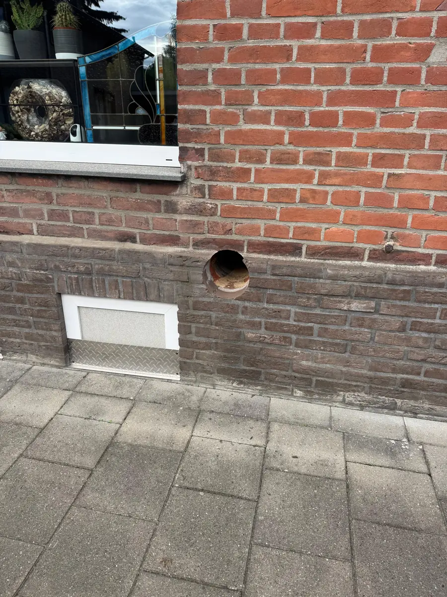 Betonboringen Echt-Susteren &mdash; doorvoer in de donkere plint naast een ventilatierooster