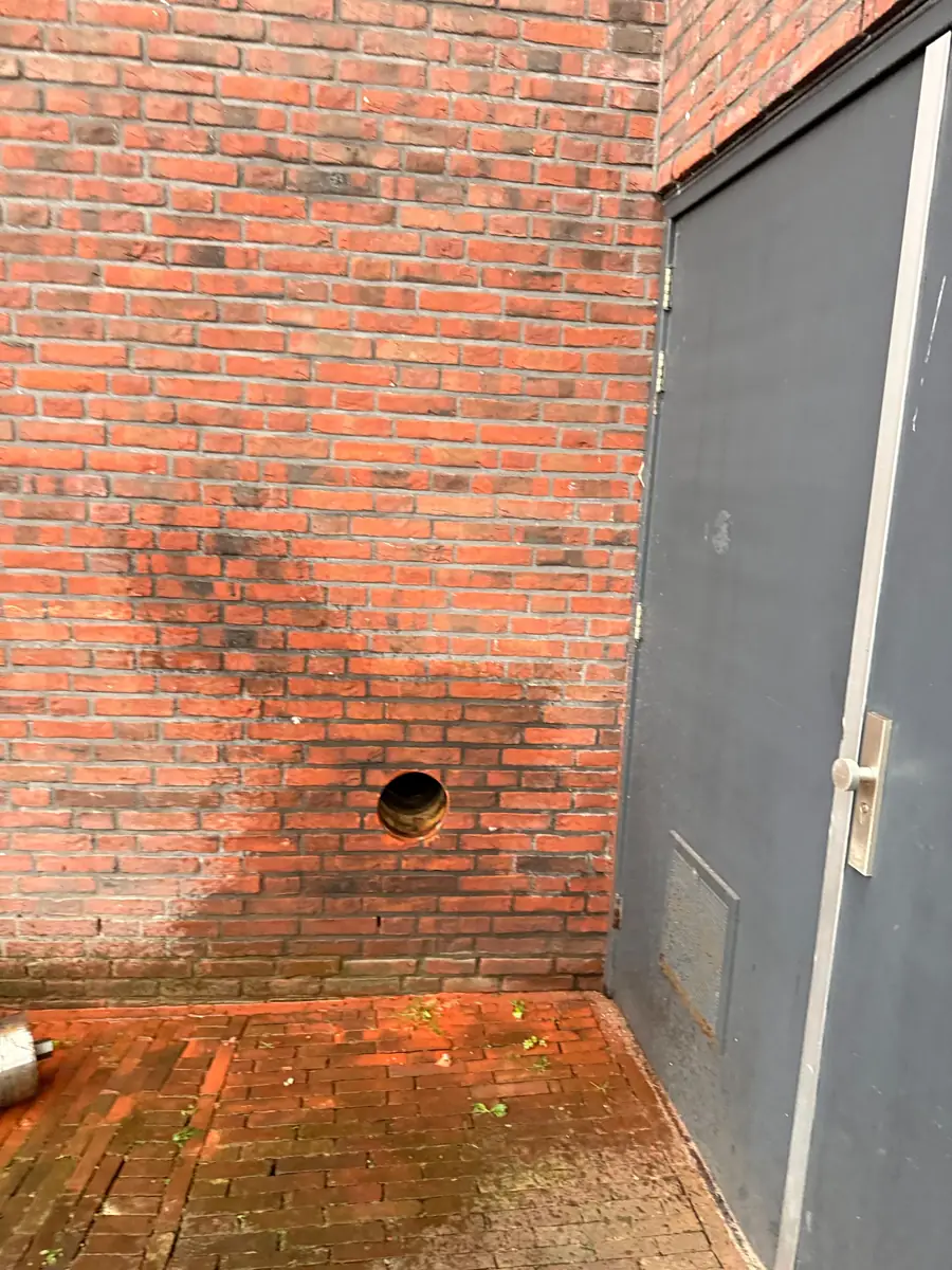 Betonboringen Gemert-Bakel &mdash; doorvoer onderin de gevel naast een grijze deur