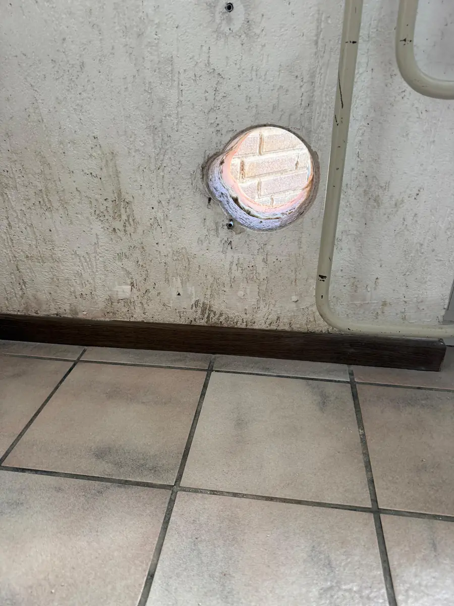 Betonboringen Heeze-Leende &mdash; doorvoer in een witte muur boven de plint en de tegelvloer