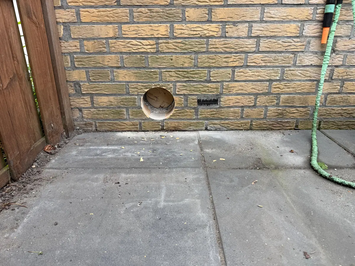 Betonboringen Laarbeek &mdash; ruime doorvoer laag in een gele tuinmuur, naast de schutting