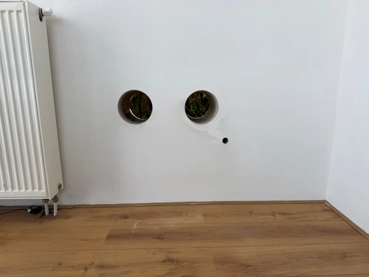 Betonboringen Leudal &mdash; twee doorvoeren voor een monoblock in een witte muur naast de radiator