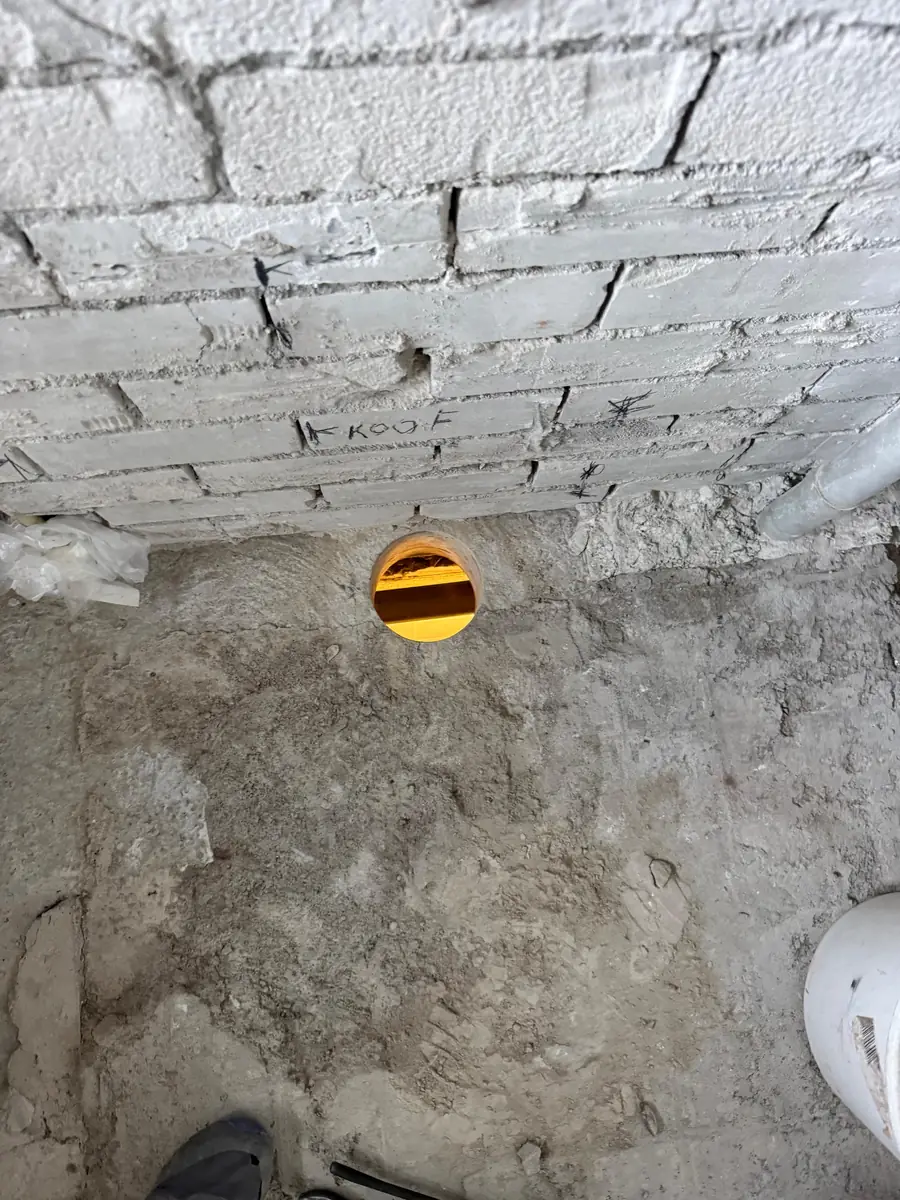 Betonboringen Maashorst &mdash; doorvoer in de vloer van een lage ruimte, tegen een oude bakstenen muur
