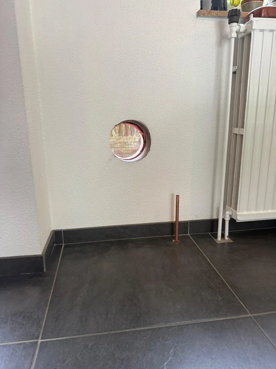 Betonboringen Nuenen &mdash; doorvoer in een witte binnenmuur naast de radiator
