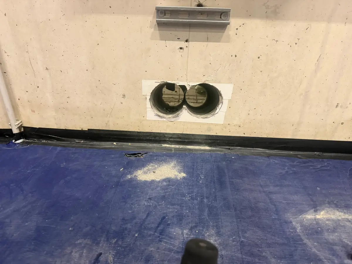 Betonboringen Oisterwijk &mdash; twee doorvoeren onderaan een betonwand, met de vloer afgedekt
