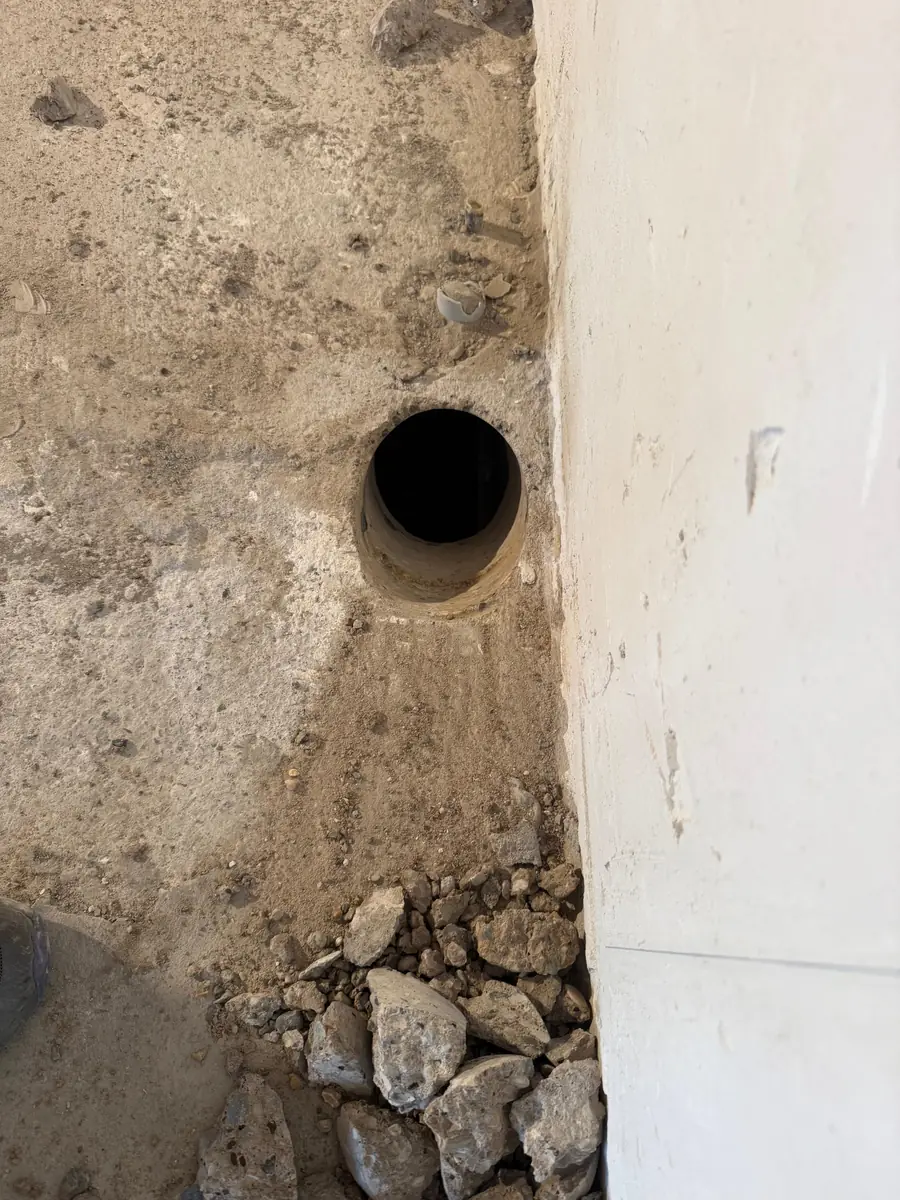 Betonboringen Roerdalen &mdash; doorvoer in een ruwe betonvloer, tegen een witte wand