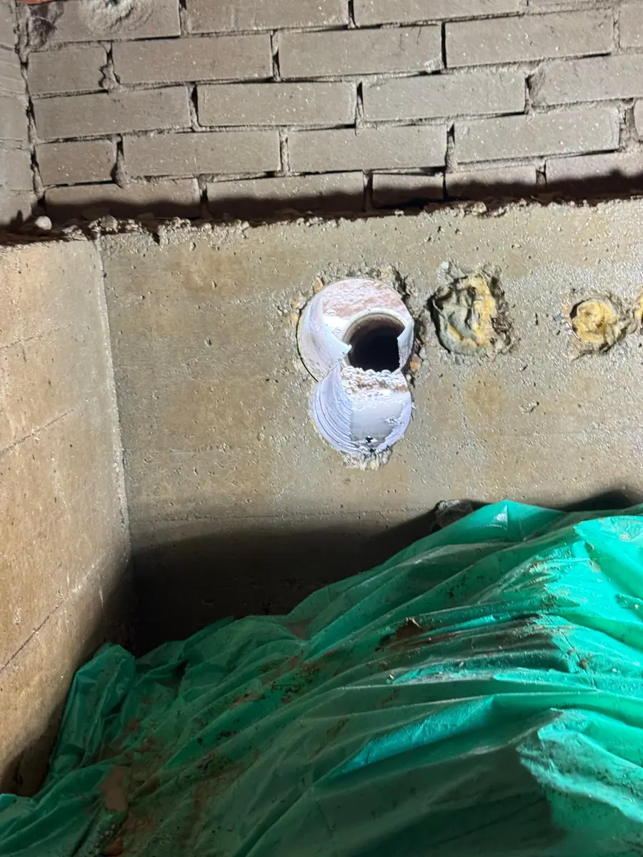 Betonboringen Roosendaal &mdash; doorvoer met witte koker in een betonwand onder het metselwerk
