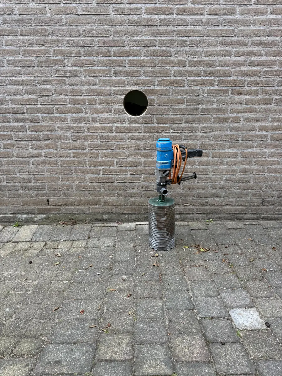 Betonboringen Stein (Limburg) &mdash; diamantboormachine op de klinkers onder een vers geboord gat in de gevel