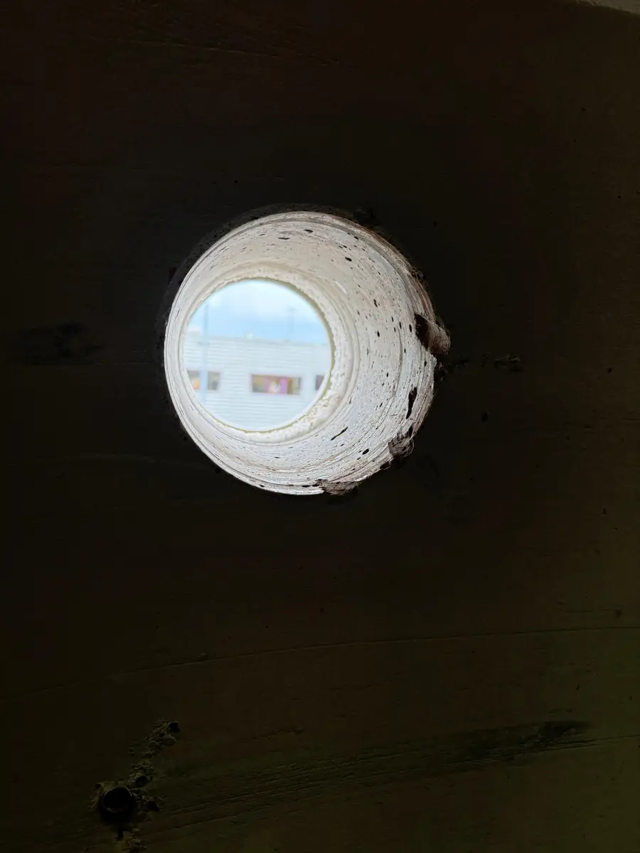 Betonboringen Valkenburg &mdash; doorvoer met witte koker door een donkere houten wand