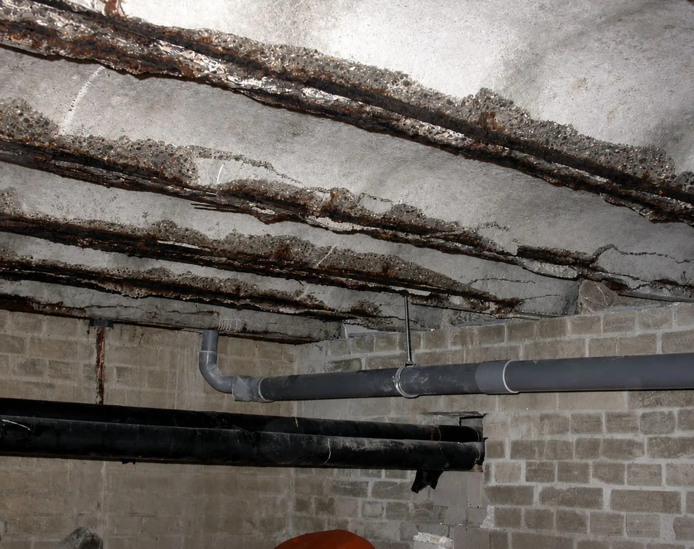 Betonrot aan de onderkant van de betonvloer, gezien vanuit de kruipruimte — roestende wapening