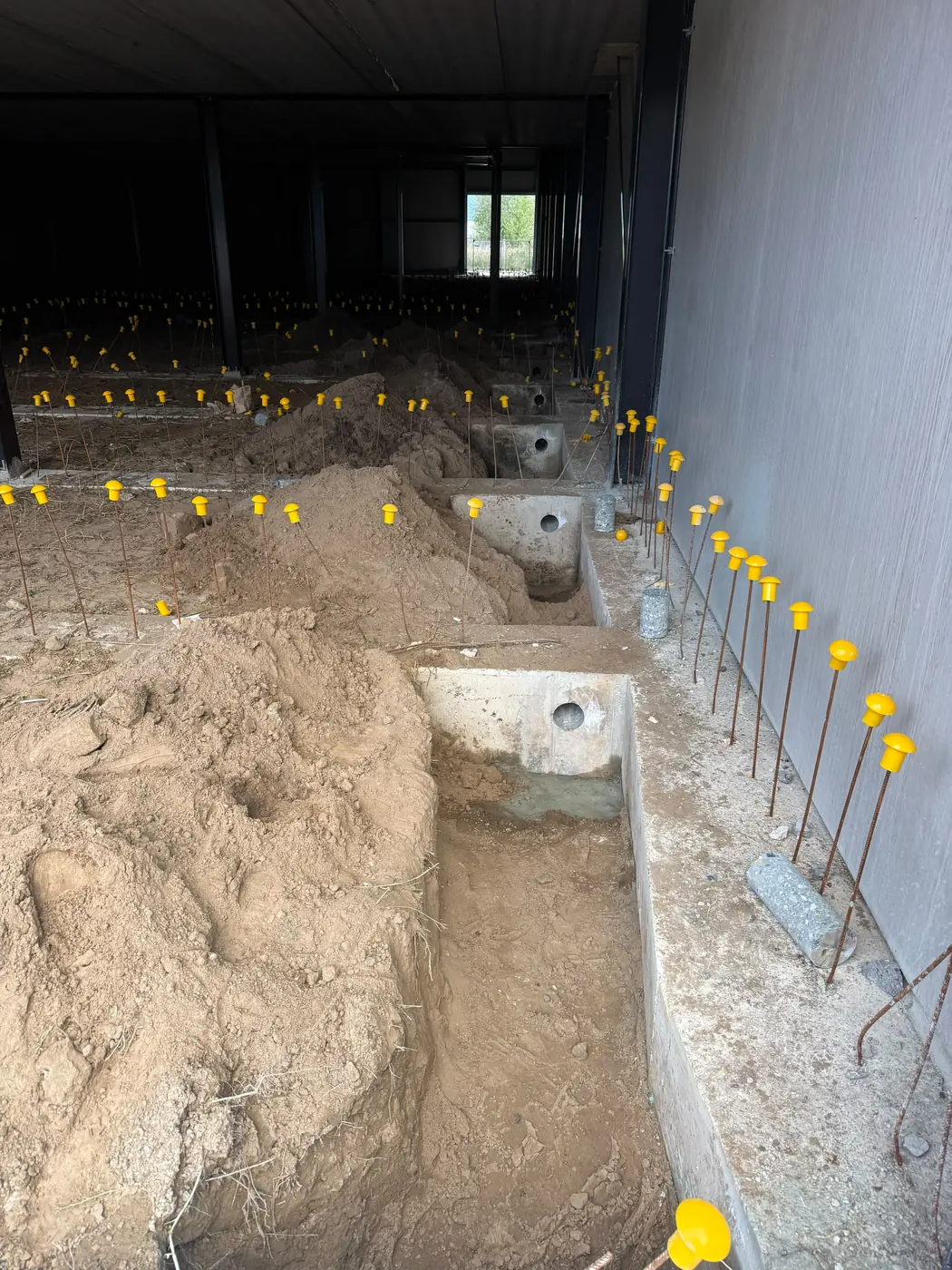 Geboord gat van 132 mm onderin een funderingsbalk, met de stekken van de vloer erboven