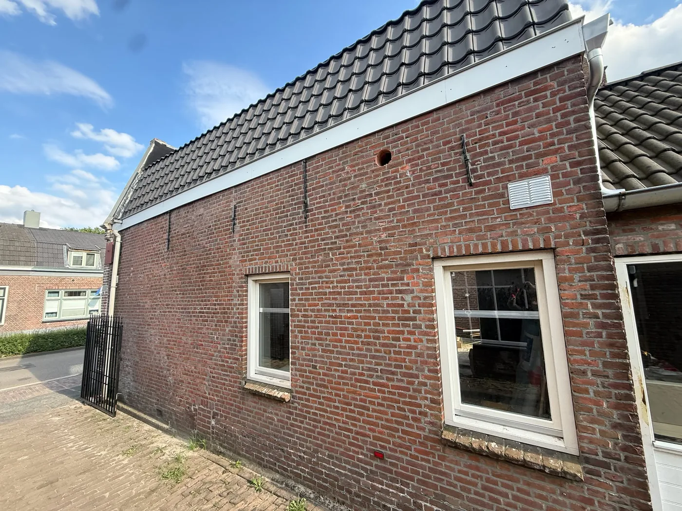 Zijgevel volsteens baksteen oud pand Weert met doorvoer hoog in de muur