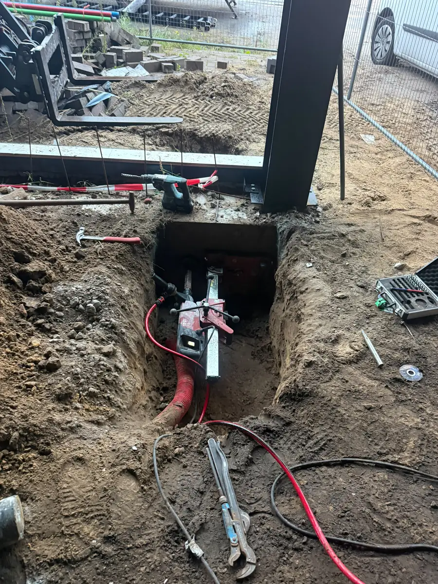 Kernboring door de funderingsbalk naast een stalen kolom, de machine ligt in de smalle put