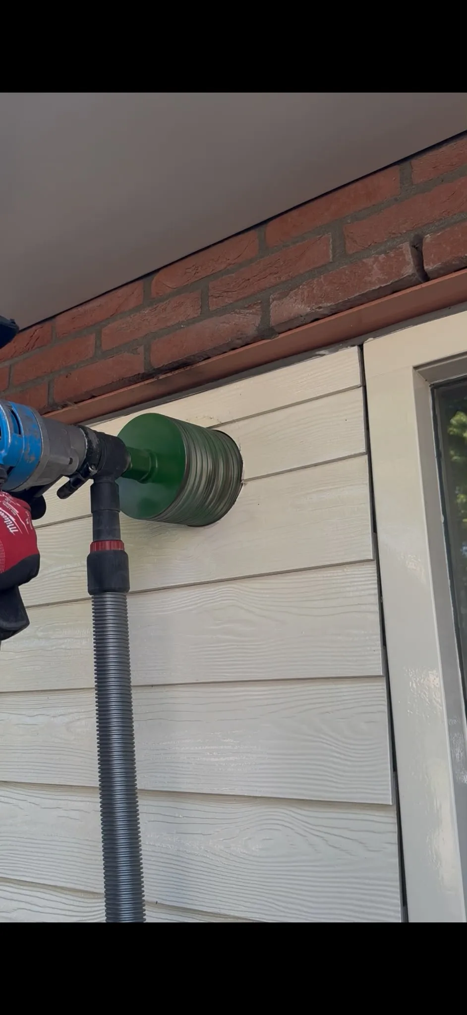 Kernboring door spouwmuur actief — Milwaukee drill met diamantboorkroon op houten gevelbekleding