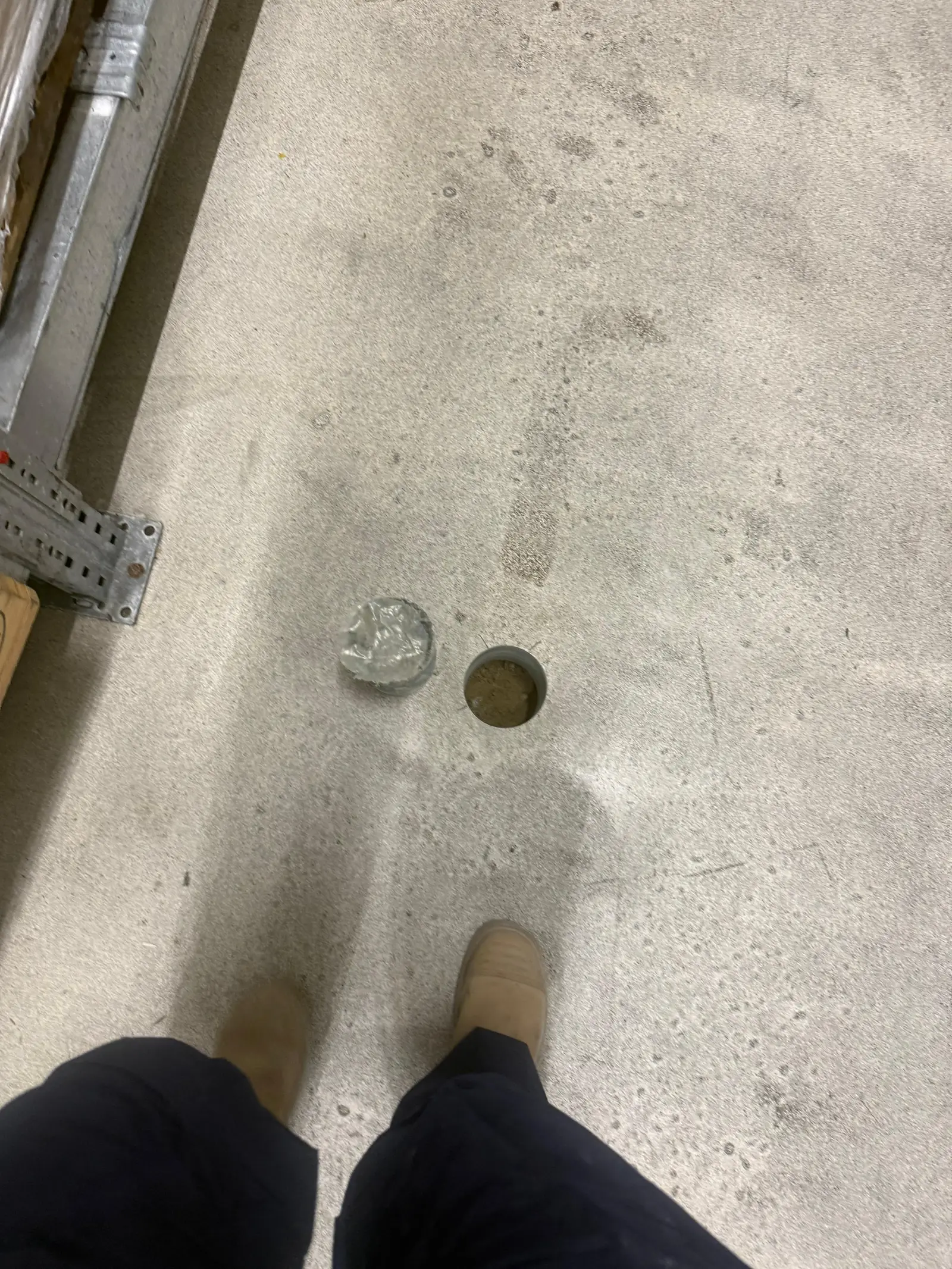 Uitgeboorde betonkern naast het boorgat in de vloer &mdash; de kern is het monster waarop de laagopbouw af te lezen is