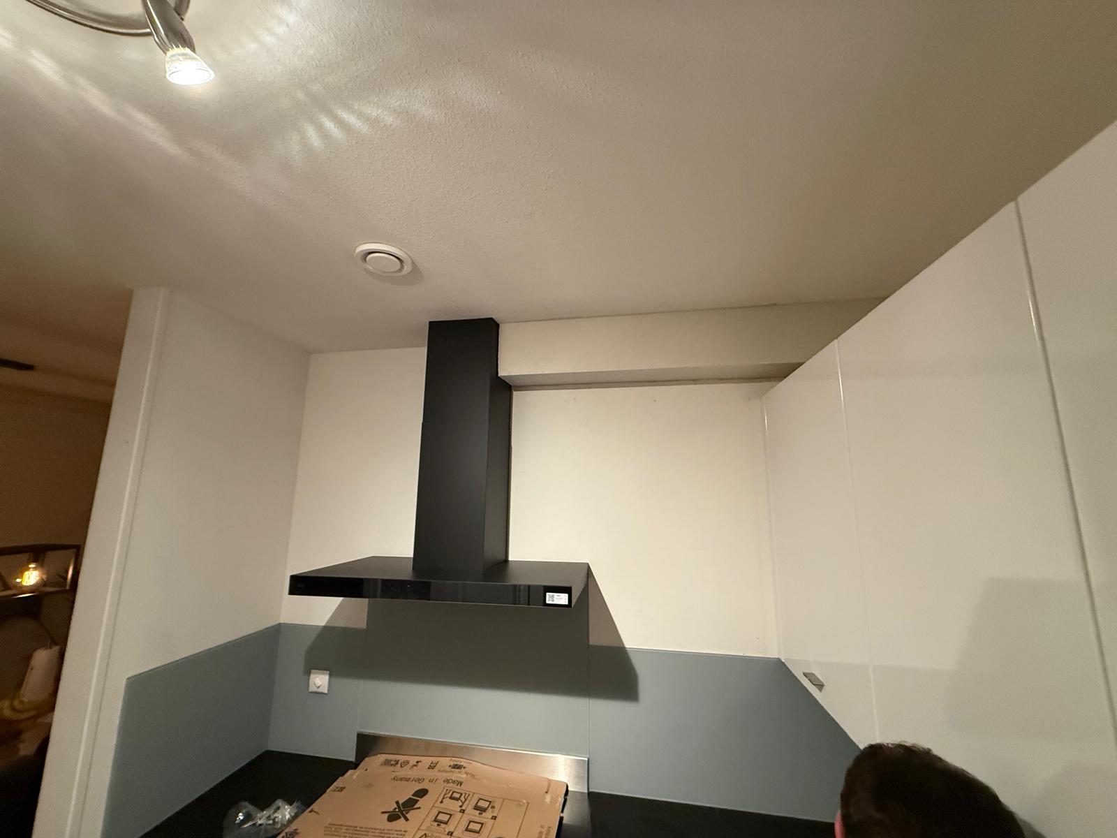 Zwarte afzuigkap installatie koof in aanbouw