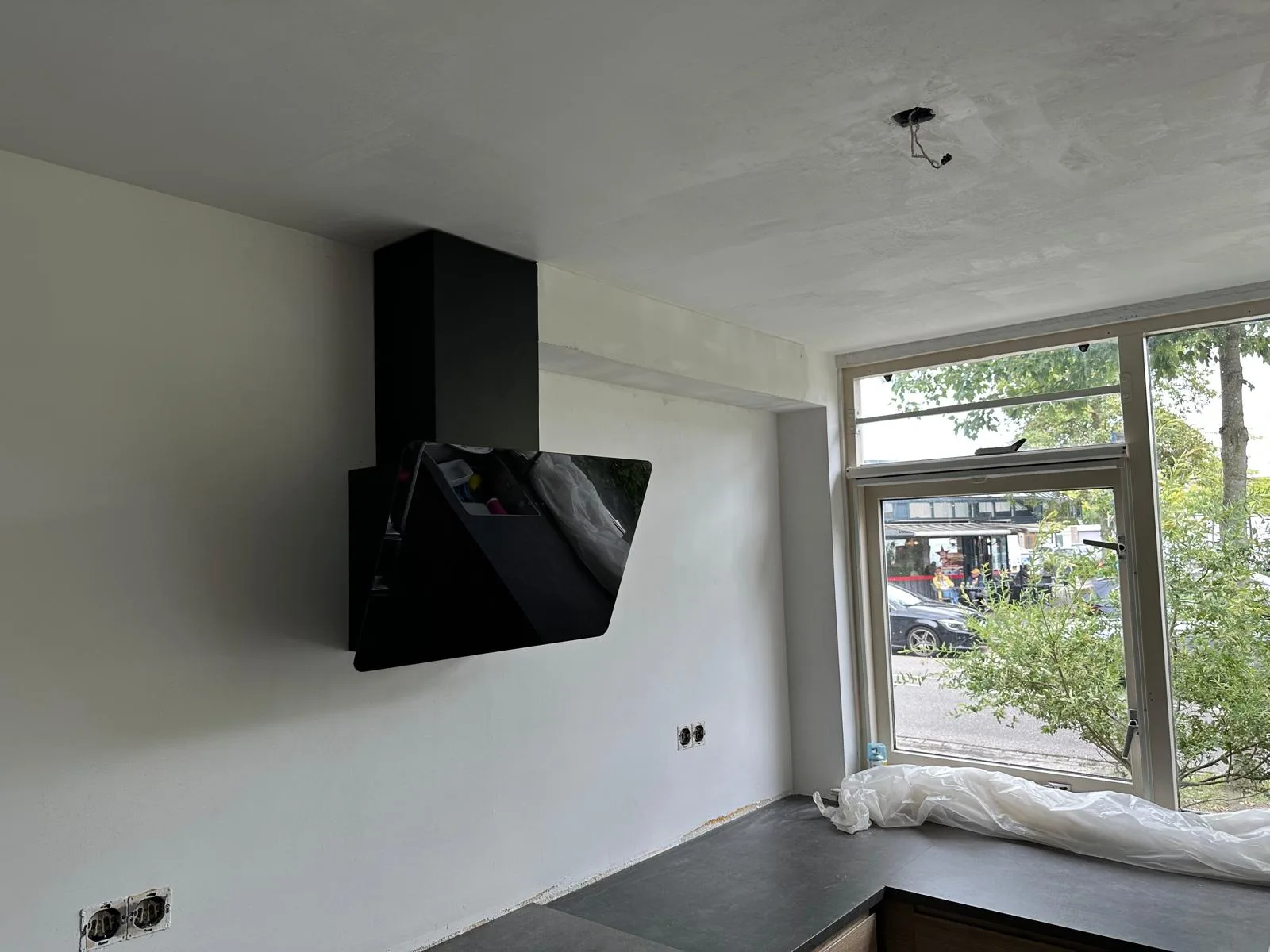 Zwarte schuine afzuigkap tegen nieuw gestuct beton