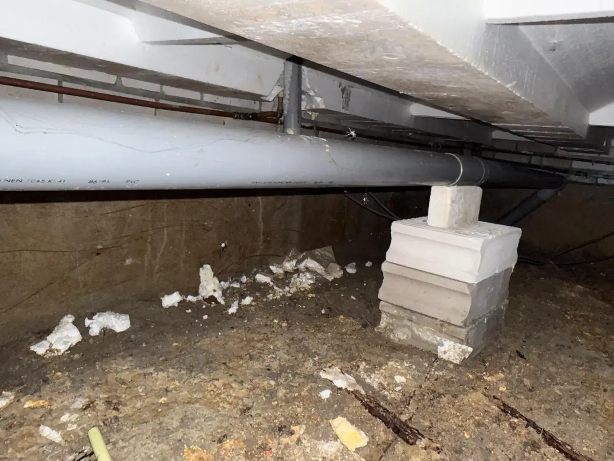 Kruipruimte ventilatie Heerlen &mdash; Kijkje in een kruipruimte: leidingen onder de vloer en een betonnen poer op de zandbodem