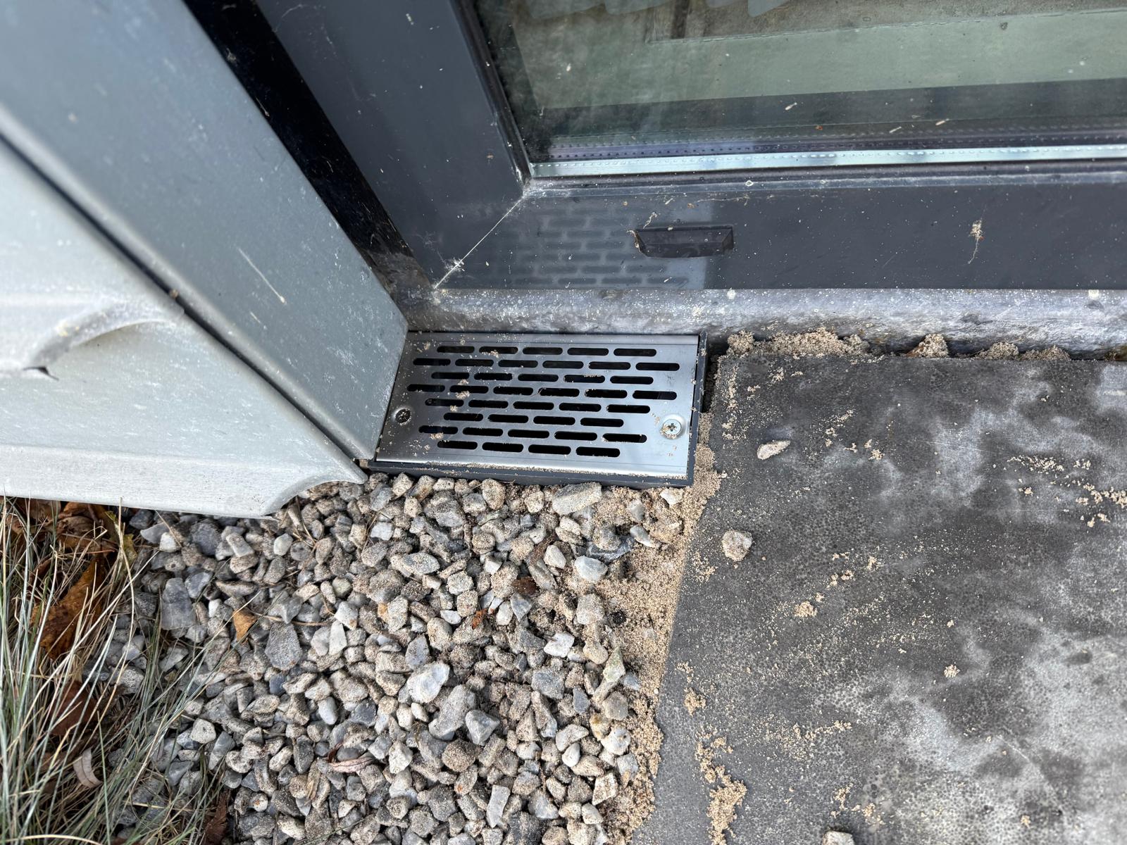Ventilatierooster in vloer naast aluminium schuifpui — nieuwbouw