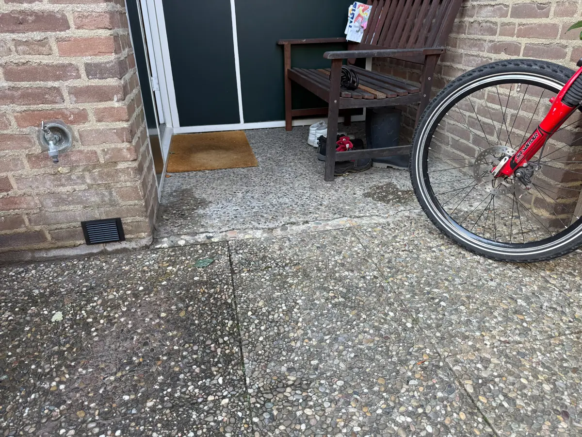 Kruipruimte ventilatie Weert &mdash; Ventilatierooster onderaan de bakstenen muur bij de achterdeur, onder de buitenkraan