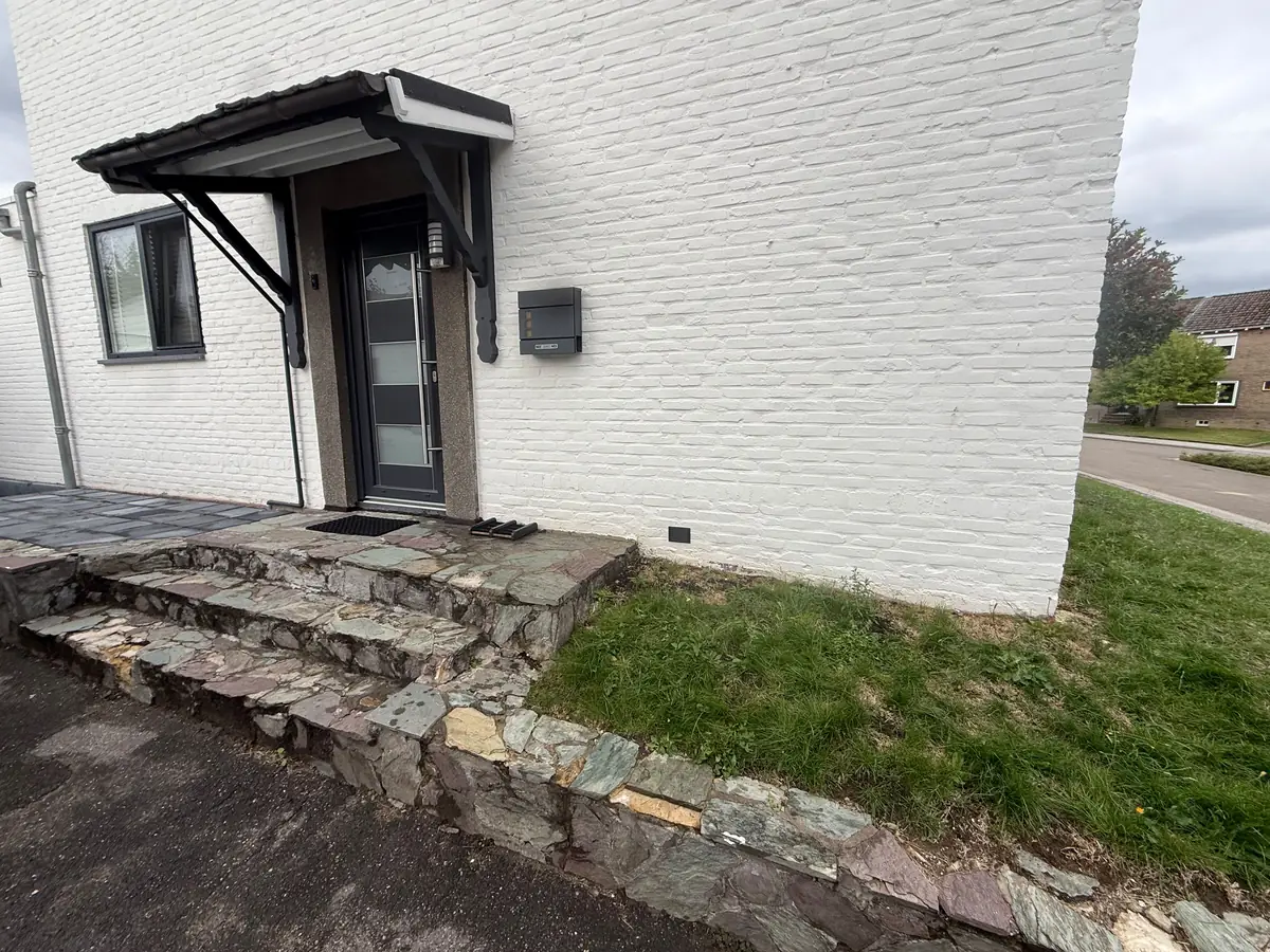Kruipruimte ventilatie Oosterhout &mdash; Witgeschilderde gevel met een stoep van natuursteen en een ventilatierooster onderaan de muur