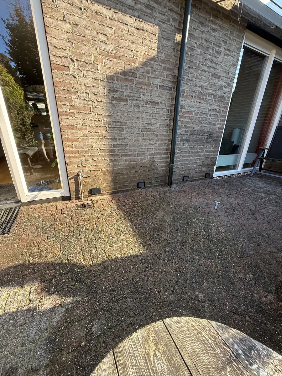 Kruipruimte ventilatie Venlo &mdash; Achtergevel met ventilatieroosters van de kruipruimte boven een klinkerterras
