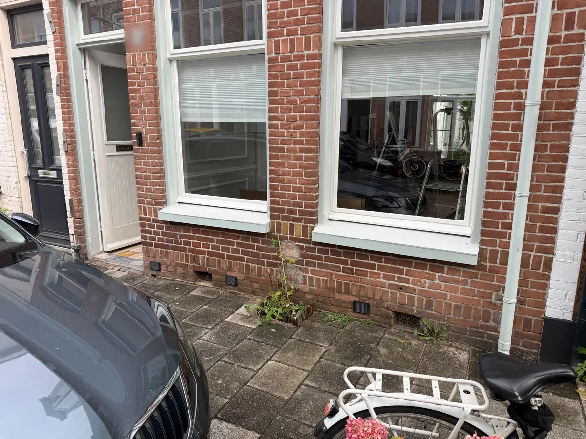 Kruipruimte ventilatie Waalwijk &mdash; Voorgevel van een tussenwoning met ventilatieroosters in de plint onder de grote ramen