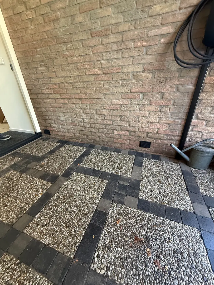 Kruipruimte ventilatie Tilburg &mdash; Terras van grindtegels met ventilatieroosters onderaan de gevel