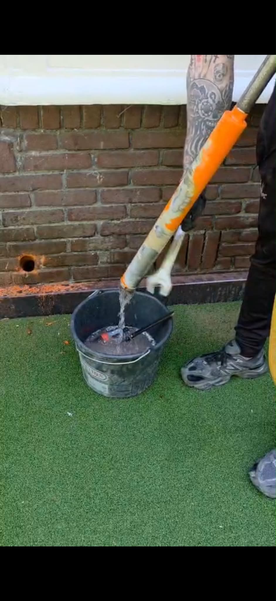 Kruipruimte ventilatie Oss &mdash; boorwater opgevangen in een emmer, het geboorde gat links in de gevel