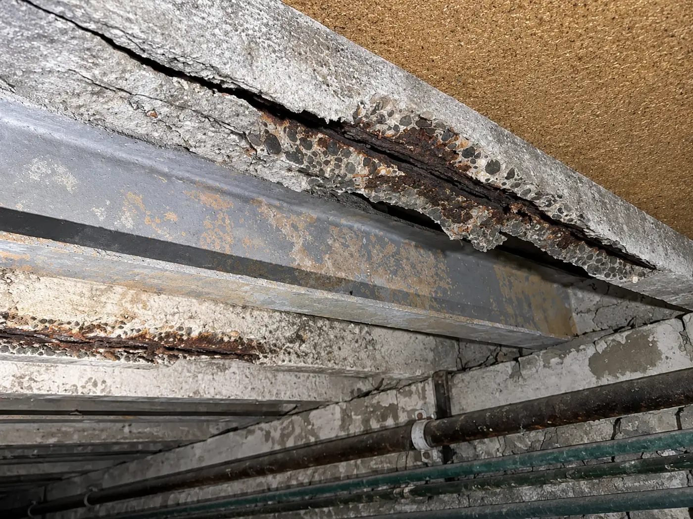 Afgespat beton met roestende wapening aan de onderkant van een mantavloer