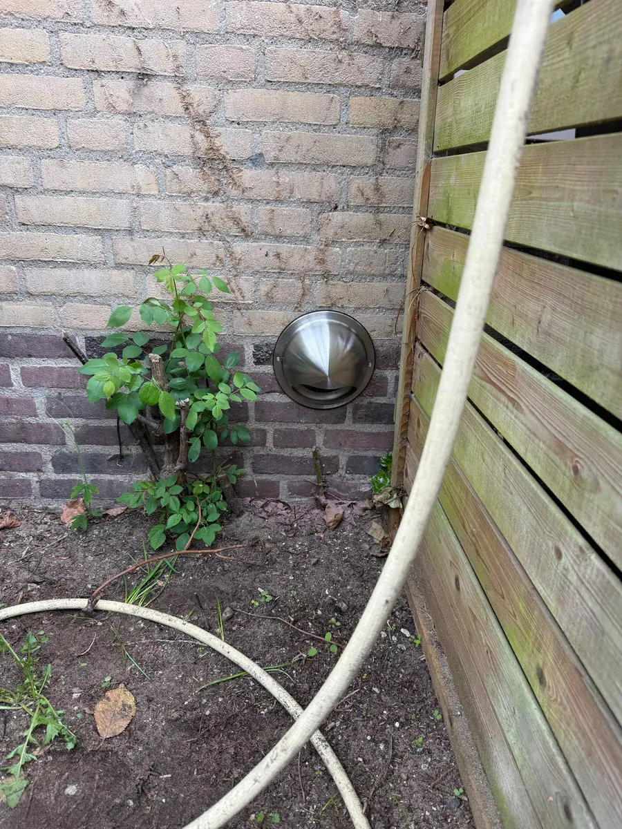 RVS-bolrooster van een afzuigkapafvoer laag in een bakstenen tuinmuur