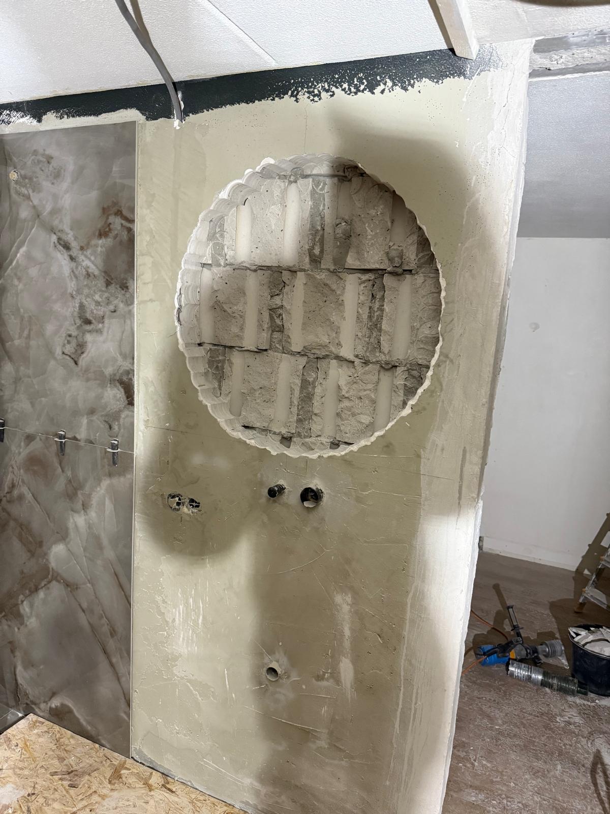 Grote ronde opening doorgebroken in bepleisterde muur badkamer renovatie