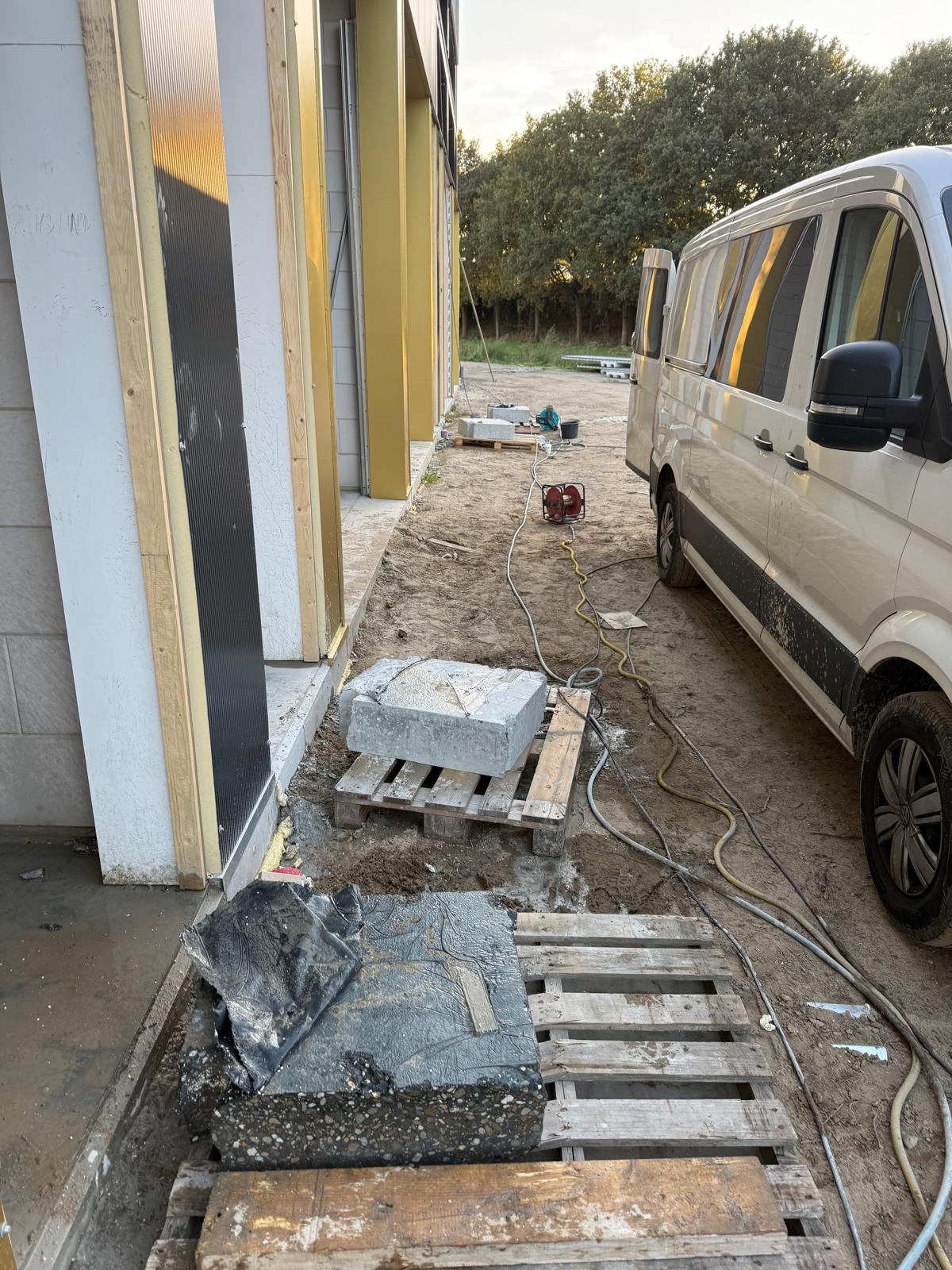 Buitensloopwerk met VW bus en gesloopte betonblokken op pallets