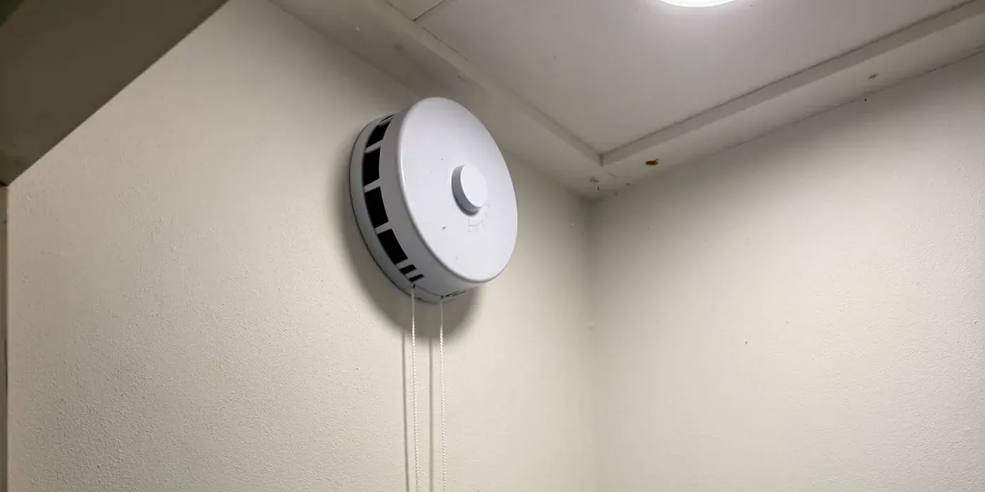 Rond regelbaar toevoerventiel hoog op een binnenmuur, met een koord om het open en dicht te zetten