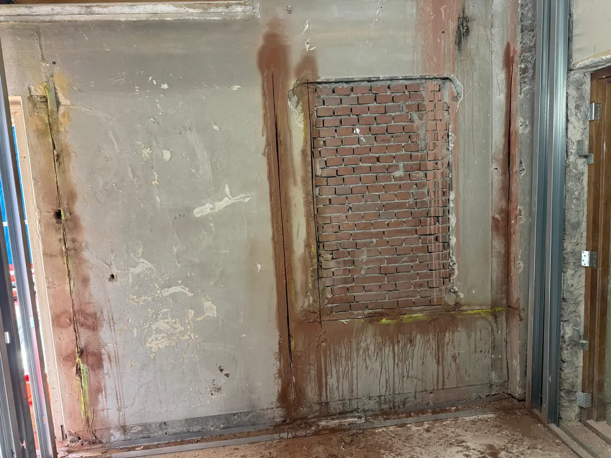 Een vak uit de volsteens bakstenen muur gezaagd, kaarsrecht op maat, in een winkelpand in Tilburg